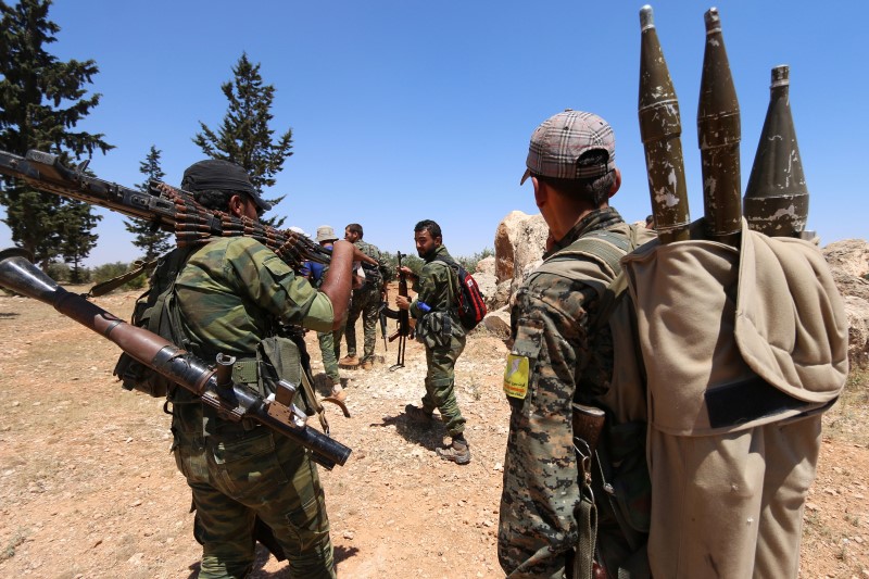 © Reuters. Fighters of the Syria Democratic Forces (SDF) carry their weapons as they walk in the western rural area of Manbij, in Aleppo Governorate