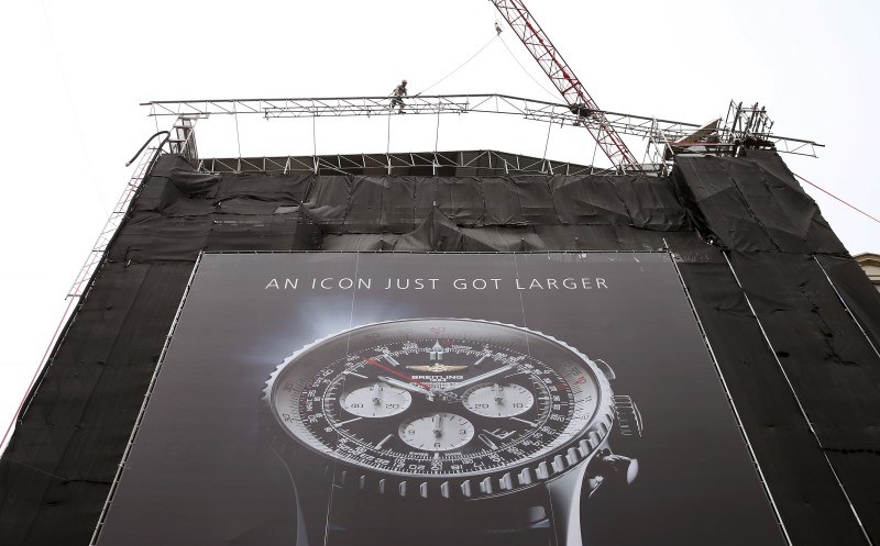 © Reuters. A construction worker climbs on a scaffolding over a huge poster advertising a Navytimer watch of Swiss manufacturer Breitling in Zurich