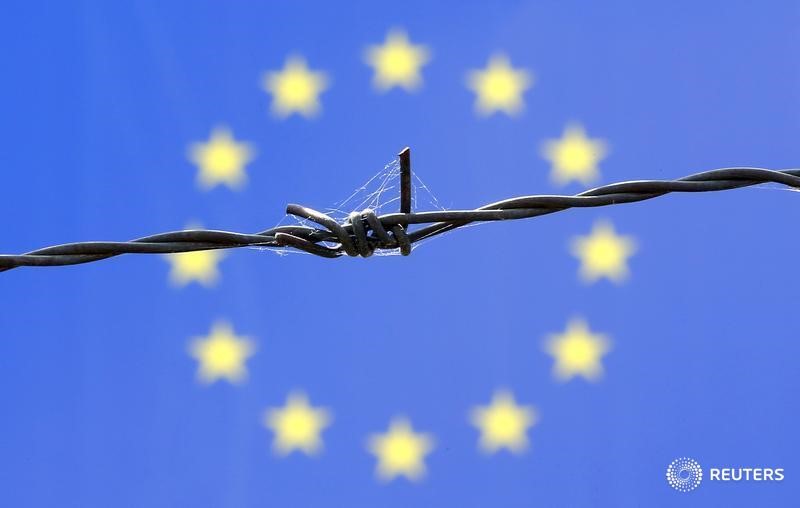 © Reuters. Колючая проволка на фоне флага ЕС в Бичке, Венгрия