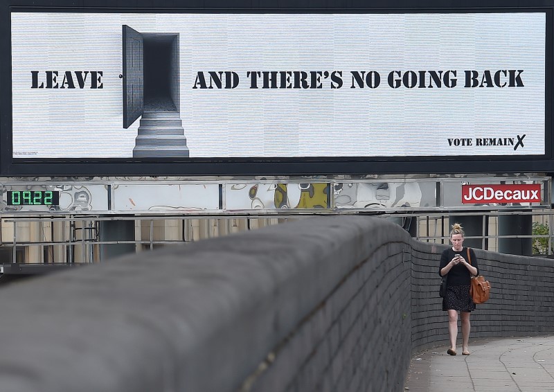 © Reuters. A woman walks near a 'Vote Remain' campaign electronic billboard in London, Britain