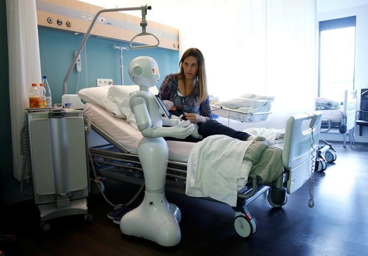 © Reuters. "Pepper" the robot stands next to a mother and her new born baby at AZ Damiaan hospital in Ostend