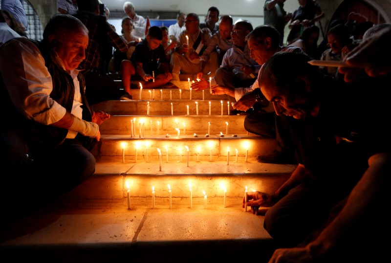 © Reuters. Jordanian people light candles during a candlelight vigil in solidarity with the Jordanian soldiers who were killed in an attack on a border military post near a camp for Syrian refugees in Amman