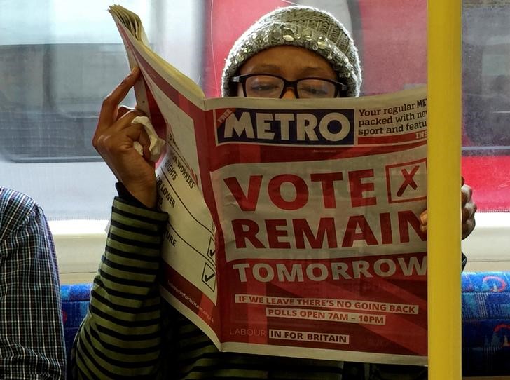 © Reuters. A woman reads a newspaper on the underground in London with a 'vote remain' advert for the BREXIT referendum