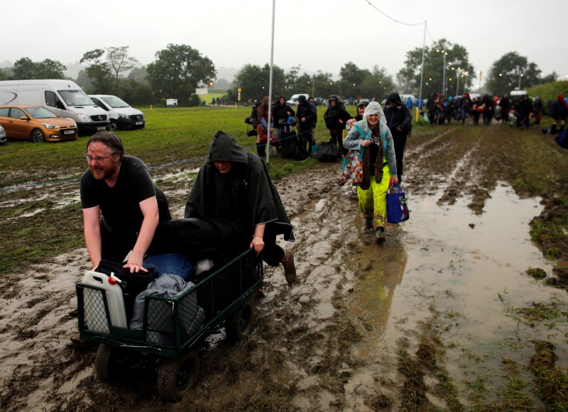 © Reuters. Revellers carry their belongings as they arrive at Worthy Farm in Somerset for the Glastonbury Festival