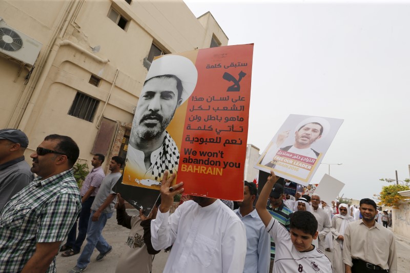 © Reuters. Protesters hold banners with photos of opposition leader and head of Al Wefaq party Ali Salman during a protest after Friday prayers in the village of Diraz west of Manama, Bahrain