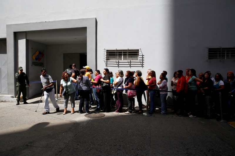 © Reuters. People stand in line as they gather outside a validation center during Venezuela’s CNE second phase of verifying signatures for a recall referendum against President Maduro, in Caracas