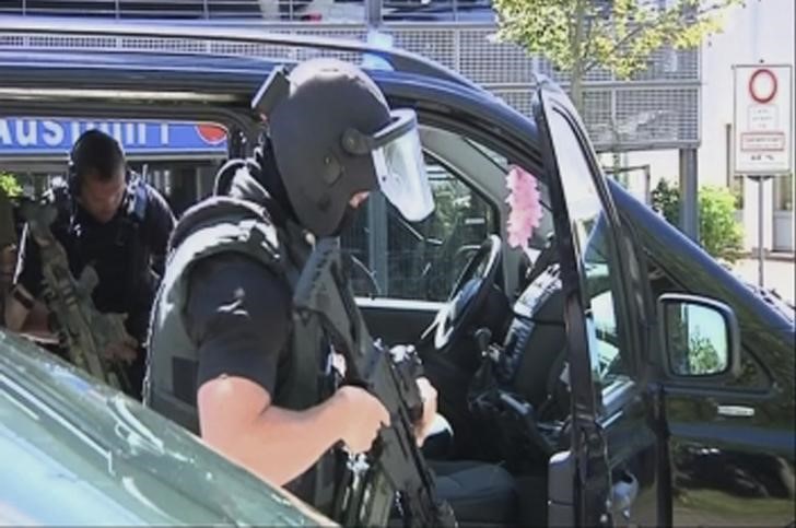 © Reuters. Сотрудники спецподразделения немецкой полиции выходят из машины перед кинокомплексом города Фирнхайм
