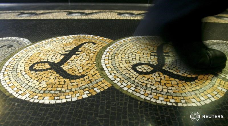 © Reuters. File photograph shows an employee walking over a mosaic depicting pound sterling symbols on the floor of the front hall of the Bank of England in London