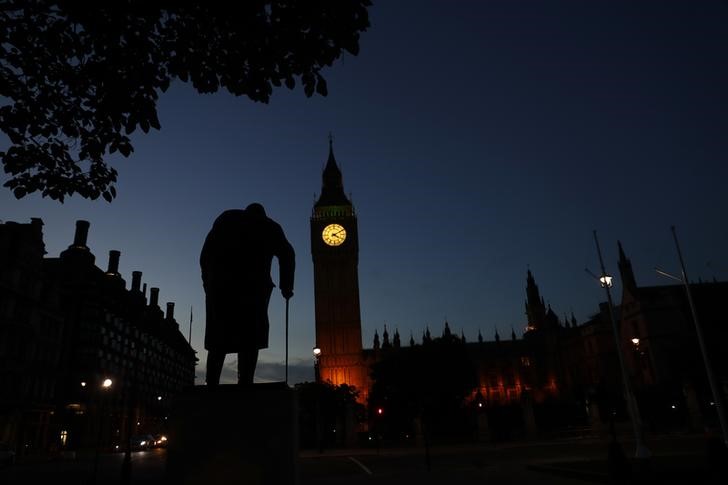 © Reuters. Вестминстерский дворец и памятник Уинстону Черчиллю на фоне предрассветного неба в Лондоне