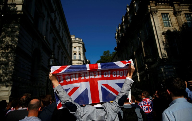 © Reuters. A vote leave supporter holds a Union flag, following the result of the EU referendum, outside Downing Street in London