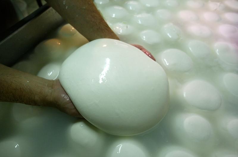 © Reuters. - PHOTO TAKEN 20AUG02 - A cheese maker helps shape a large mozzarella made from buffalo milk at the ..