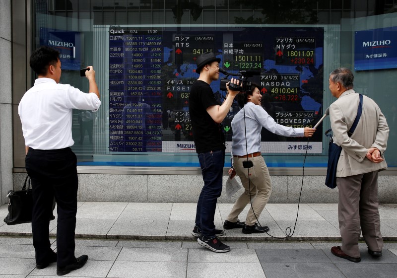 © Reuters. A journalist interviews a man after he read market indices on a screen outside a brokerage in Tokyo
