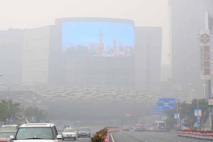 © Reuters. A electric screen showing Shanghai Pudong financial area in a clear day, is seen amid heavy smog in Shanghai