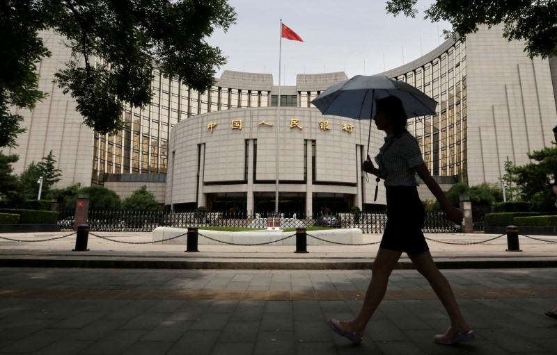 © Reuters. Woman walks past the headquarters of the PBOC in Beijing