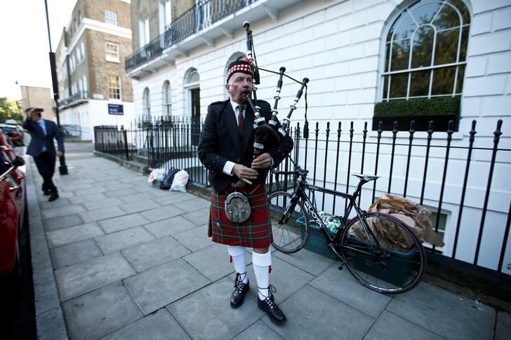 © Reuters. A lone piper plays his bagpipes outside the home of former London Mayor Boris Johnson