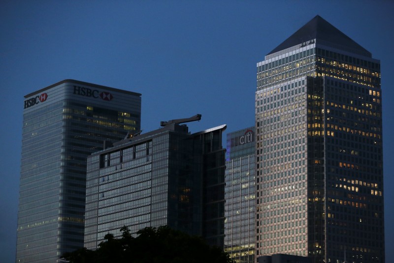 © Reuters. Office lights are on in banks as dawn breaks behind the financial district of Canary Wharf, in London