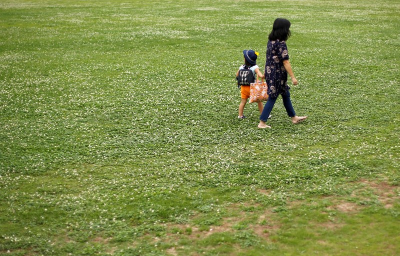 © Reuters. Foster mother Yoshinari and her foster child walk at a park near her home in Inzai