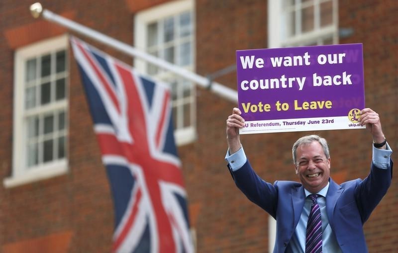 © Reuters. Leader of the United Kingdom Independence Party Nigel Farage holds a placard as he launches his party's EU referendum tour bus in London