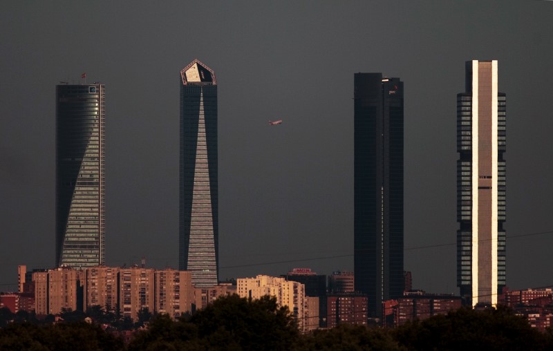 © Reuters. A passenger plane is framed by buildings in the Cuatro Torres Business Area as its takes off at dusk from Madrid's Adolfo Suarez Barajas airport