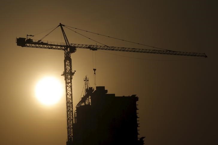 © Reuters. A crane at a construction site is silhouetted against the rising sun in Beijing