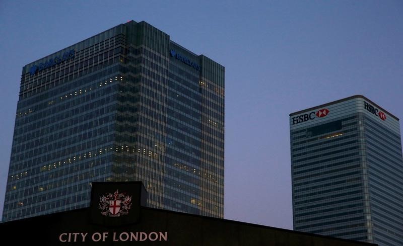 © Reuters. Office lights are on in banks as dawn breaks behind the financial district of Canary Wharf, in London