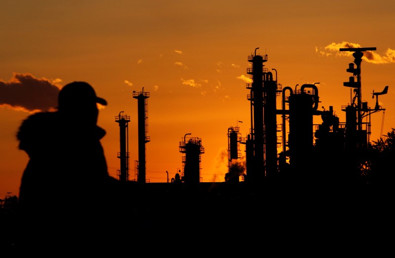 © Reuters. A man walks past chimneys at an industrial district during sunset in Tokyo