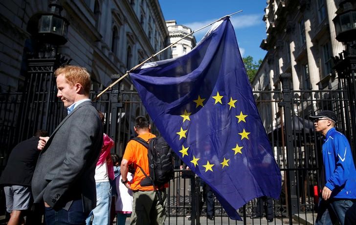 © Reuters. A man carries a EU flag, after Britain voted to leave the European Union, outside Downing Street in London