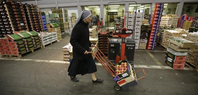 © Reuters. A nun pushes a trolley with apples at the fruits and vegetables pavilion in Rungis International food market as buyers prepare for the Christmas holiday season in Rungis, south of Paris