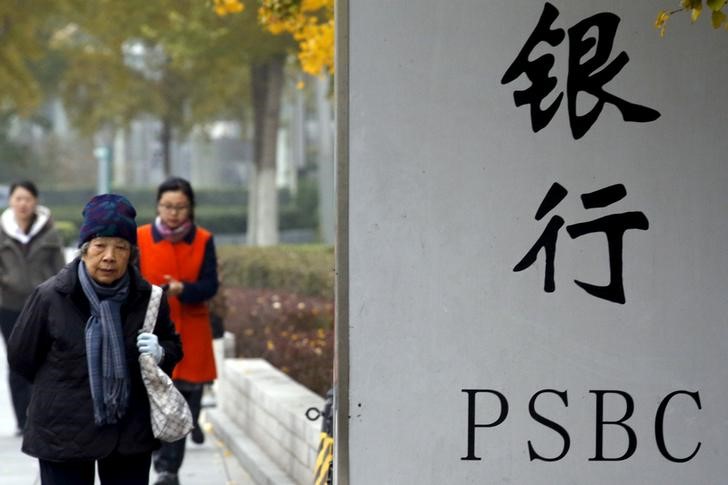© Reuters. People walk past a sign outside a branch of Postal Savings Bank of China (PSBC) in downtown Beijing