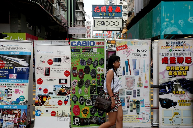 © Reuters. A woman walks past advertisements from nearby retail shops at Mongkok shopping district in Hong Kong