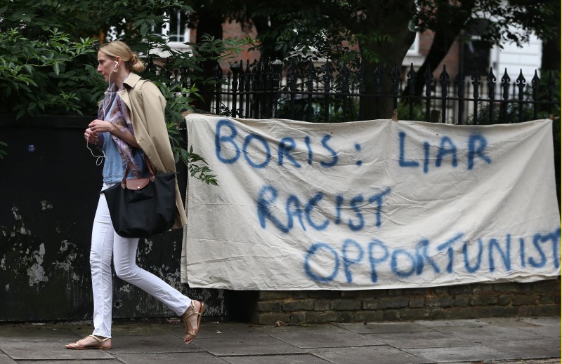 © Reuters. A woman walks past a protest banner attached to railings outside the home of former mayor of London Boris Johnson, in London