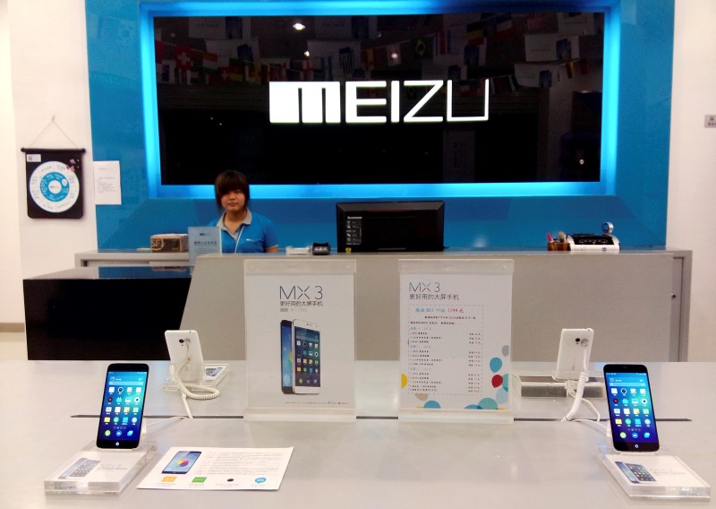 © Reuters. Shop assistant waits for customers at a Meizu store as Meizu MX3 smartphones are seen on display in the foreground, in Shenzhen