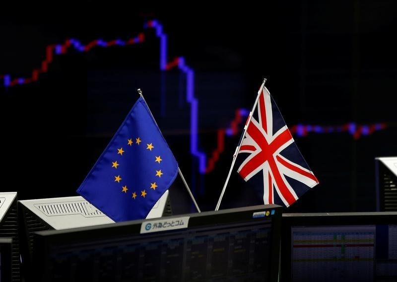 © Reuters. A British flag and an EU flag are seen in front of a monitor displaying a graph of the Japanese yen's exchange rate against the U.S. dollar at a foreign exchange trading company in Tokyo