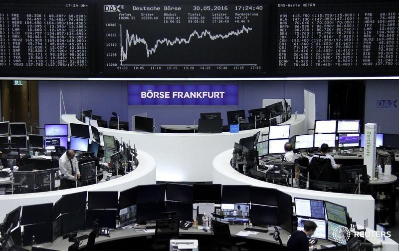 © Reuters. Traders work at their desks in front of the German share price index, DAX board, at the stock exchange in Frankfurt