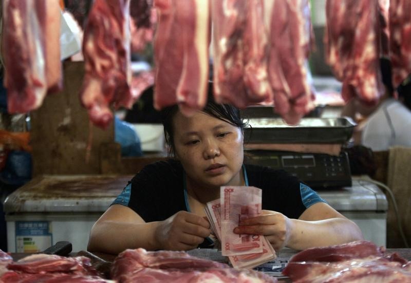 © Reuters. Продавщица мяса на рынке китайского города Чунцин считает деньги