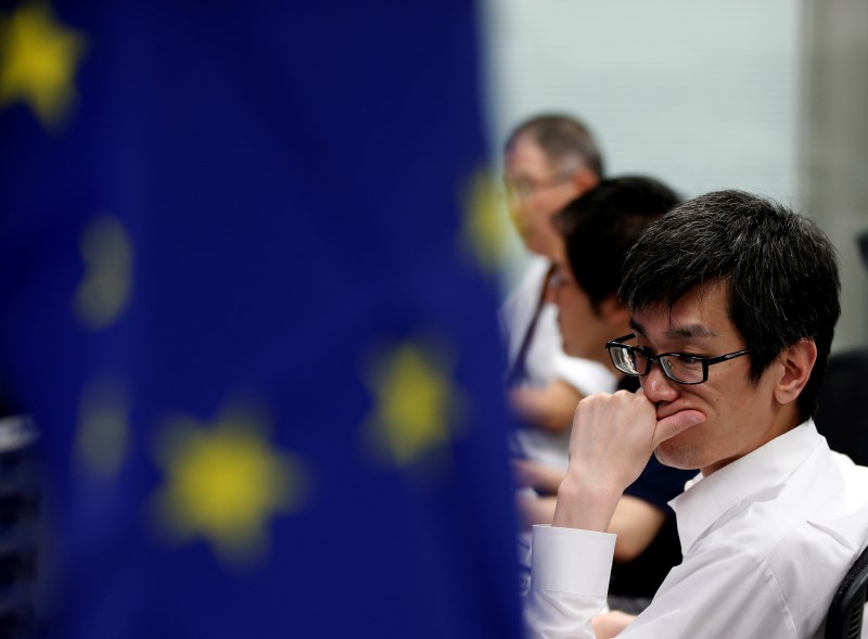 © Reuters. Employees of a foreign exchange trading company work next to an EU flag in Tokyo