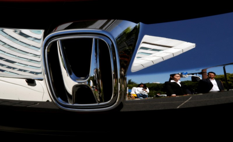 © Reuters. People are reflected on a Honda Motor car outside the company's showroom in Tokyo
