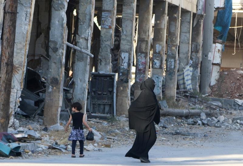 © Reuters. Residents walk past damaged buildings in the rebel held area of Aleppo's Bab al-Hadeed district