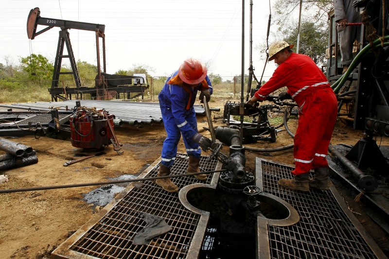 © Reuters. Men work at an oil pump in Lagunillas, Ciudad Ojeda