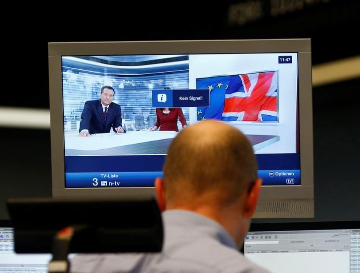 © Reuters. A trader works in front of a news broadcast on a TV at the stock exchange in Frankfurt