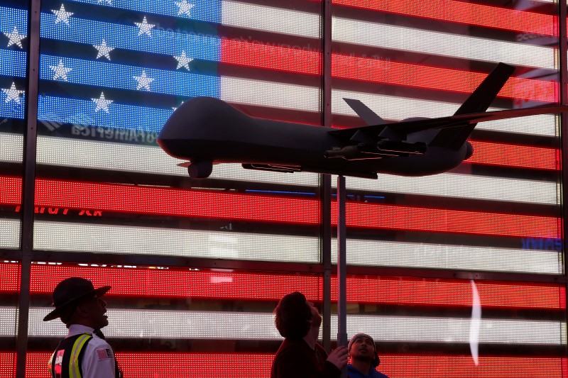 © Reuters. An official instructs two protesters to lower their Reaper drone model as they take part in a protest in Times Square in Manhattan