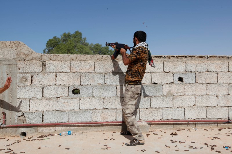 © Reuters. A fighter from forces aligned with Libya's new unity government fires a weapon from atop a house in Sirte