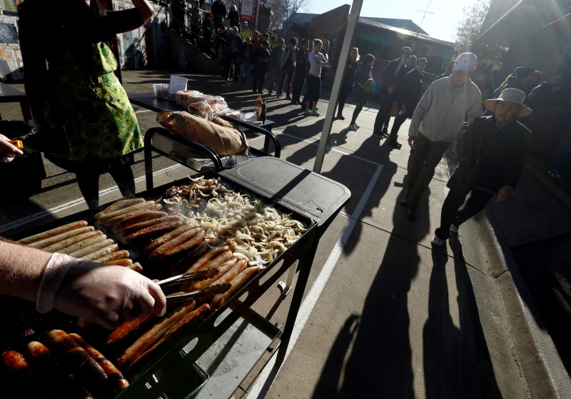 © Reuters. A traditional Australian 'sausage sizzle' barbeque offers sausage-and-onion sandwiches to hungry voters as they queue up at a polling station at Mount Alexander College in Flemington