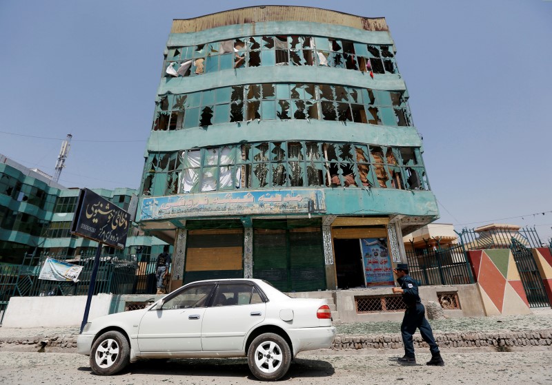 © Reuters. An Afghan policeman walks past a damaged building after a suicide attack in Jalalabad city, Afghanistan