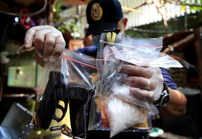 © Reuters. A member of the Philippine National Police investigation unit shows confiscated methamphetamine, known locally as Shabu, along with illegal firearms seized from suspected drug pushers during an operation by the police in Quiapo city, metro Manila