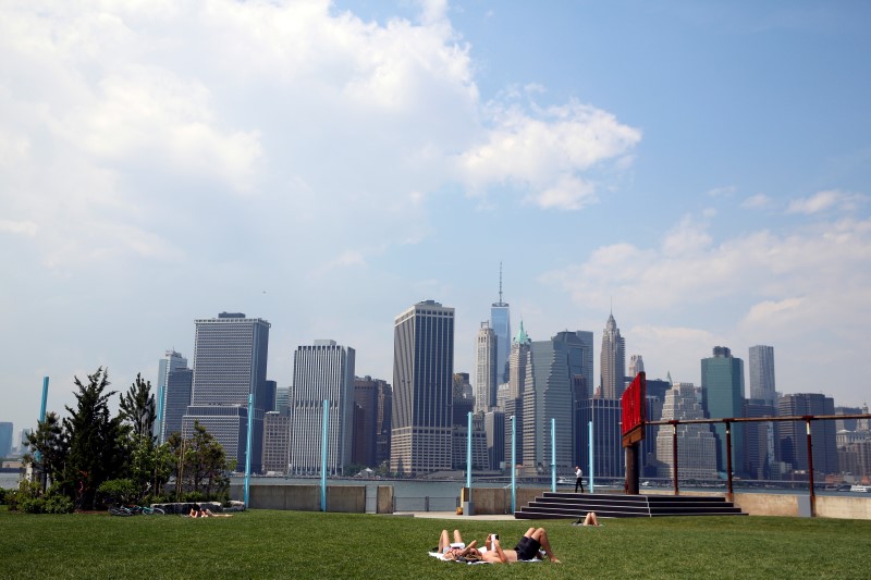 © Reuters. The skyline of lower Manhattan is seen as people lay on the grass in Brooklyn Bridge Park in New York