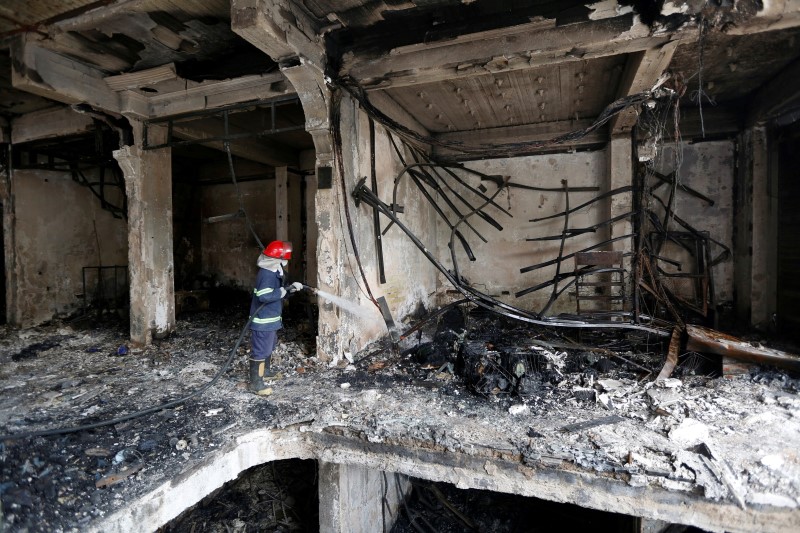 © Reuters. Bombeiro jogando água em local de explosão em Bagdá