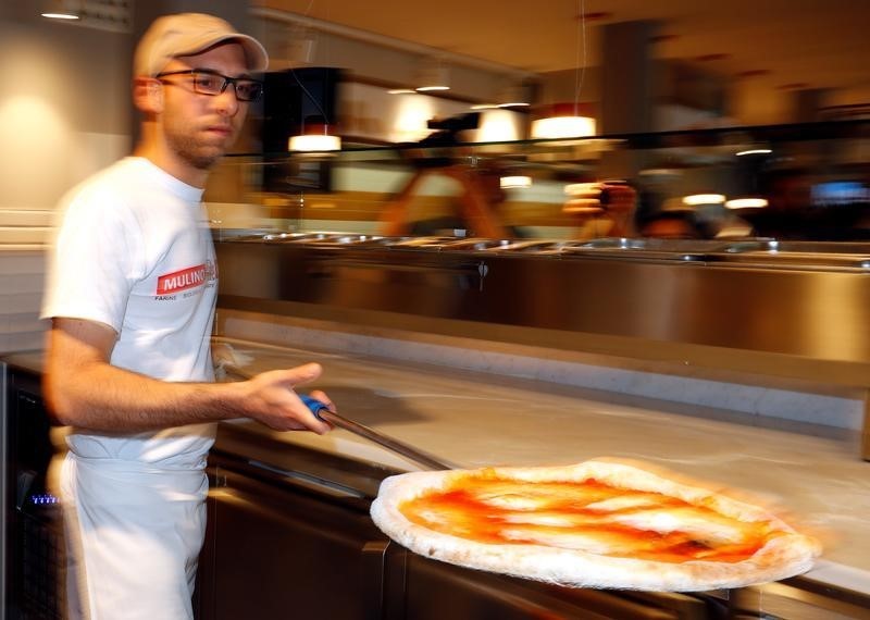 © Reuters. A staff member serves pizza margherita's at the Eataly motorway restaurant on highway in Modena