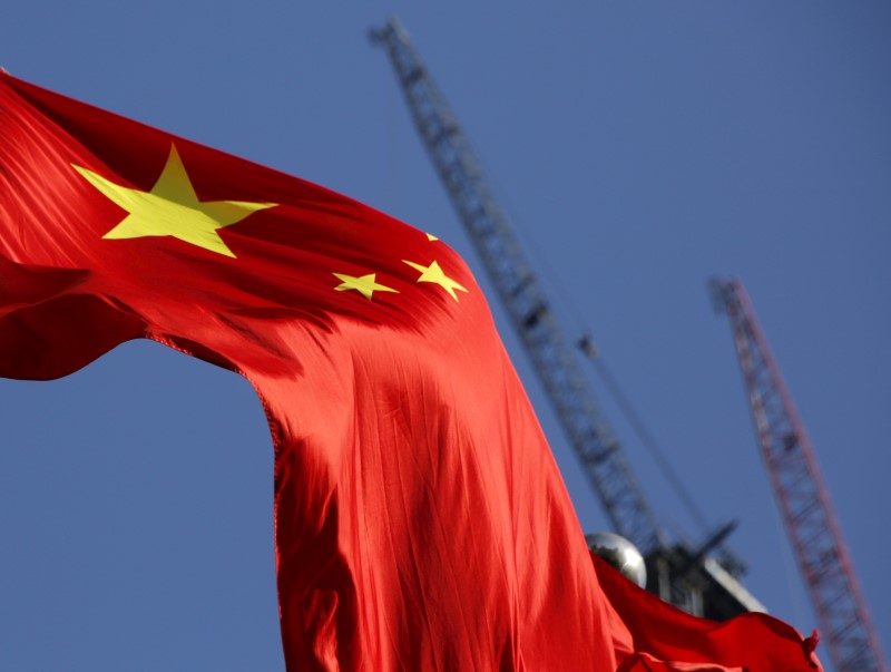 © Reuters. China's national flag is seen in front of cranes on a construction site at a commercial district in Beijing