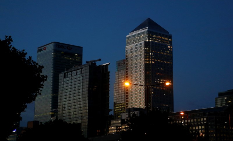 © Reuters. Office lights are on in banks as dawn breaks behind the financial district of Canary Wharf, in London